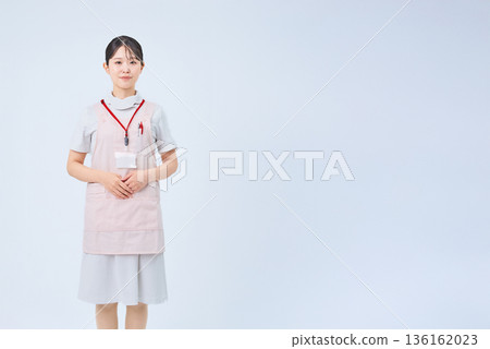 A young woman wearing a white coat and apron A young woman wearing a white coat and apron 136162023