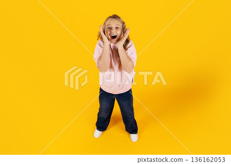 Excited preteen girl reacting with surprise and joy, standing on yellow background Excited preteen girl reacting with surprise and joy, standing on yellow background 136162053