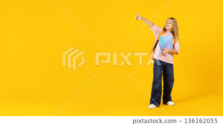 Preteen student girl pointing aside at copy space confidently while holding notebook 136162055