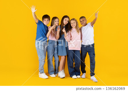 Group of happy preteen children standing together on yellow studio background Group of happy preteen children standing together on yellow studio background 136162069