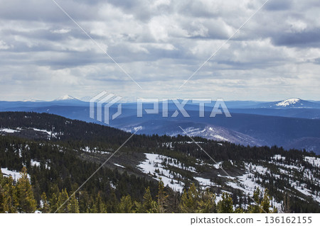 Snow on coniferous mountain slope under cloudy sky. Beautiful nature landscape of vast forest mountain range. Wilderness terrain backdrop. 136162155