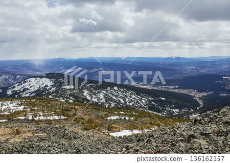 Mountain landscape with snow-covered slopes and sparse trees under a cloudy sky. Scenic nature view for travel and adventure concept. Mountain landscape with snow-covered slopes and sparse trees under a cloudy sky. Scenic nature view for travel and adventure concept. 136162157