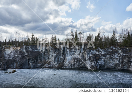 Frozen marble quarry in Ruskeala Mountain Park with evergreen forest on cliff top. Winter landscape for travel and nature concept. 136162164