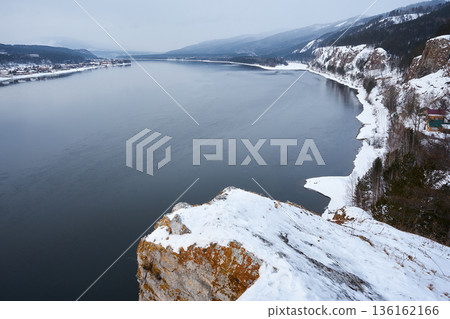 Yenisei river view from Karaulnensky cliff in winter. Wide scenic landscape with water, snow, and forest. Travel destination Siberia. 136162166