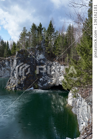 Majestic Ruskeala mountain park with deep emerald water and rocky cliffs. Nature wonderland with green trees, blue sky for spring travel. 136162181
