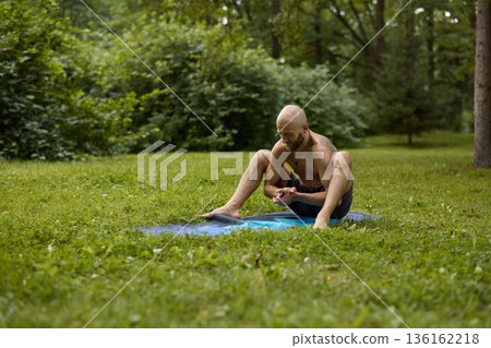 White male wellness coach performing seated hip opener White male wellness coach performing seated hip opener 136162218