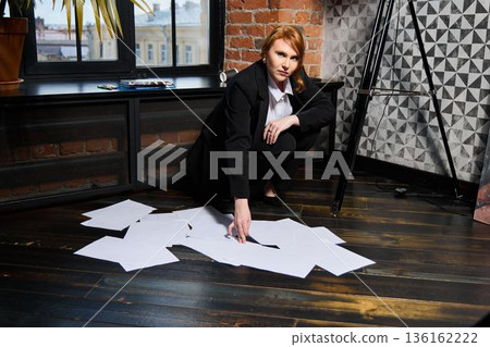 Careful editor scrutinizing printed proofs near brick wall background 136162222