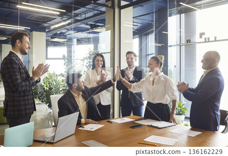 Smiling colleagues give high five and applause after successful office presentation Smiling colleagues give high five and applause after successful office presentation 136162229