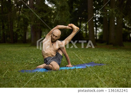 Individual engaged in mindful stretching amidst peaceful green surroundings 136162241