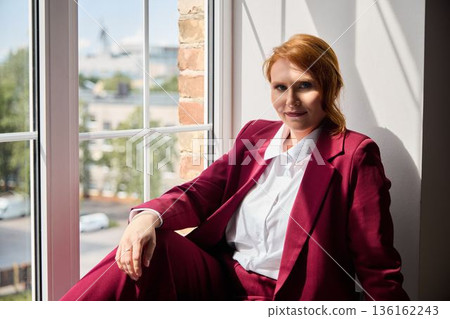 Stylish woman in burgundy suit looks over urban cityscape Stylish woman in burgundy suit looks over urban cityscape 136162243