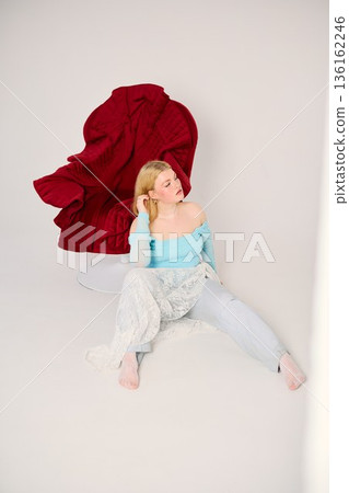 Influencer in trendy outfit sits on striking red sculpture chair Influencer in trendy outfit sits on striking red sculpture chair 136162246