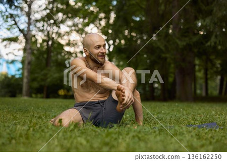 Person smiling contentedly following exercise on grassy outdoor area 136162250