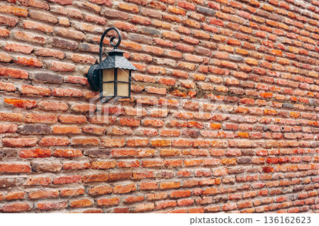 Light fixture on brick wall in a rustic setting at an outdoor location 136162623