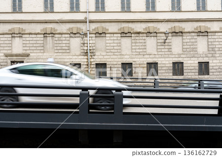 Cars drive on a bridge near an old building during a cloudy day in the city Cars drive on a bridge near an old building during a cloudy day in the city 136162729