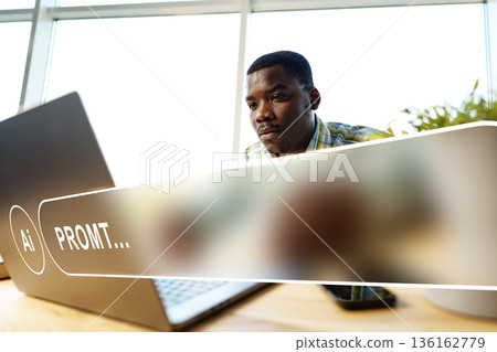 Man working on laptop with artificial intelligence prompt in office during daytime 136162779