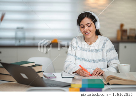 Smiling woman studying at home focused on online education Smiling woman studying at home focused on online education 136162835