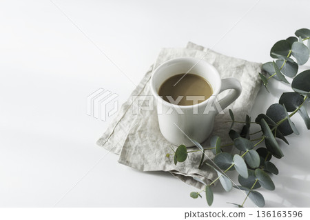 White mug of coffee and eucalyptus (minimal, white space) White mug of coffee and eucalyptus (minimal, white space) 136163596