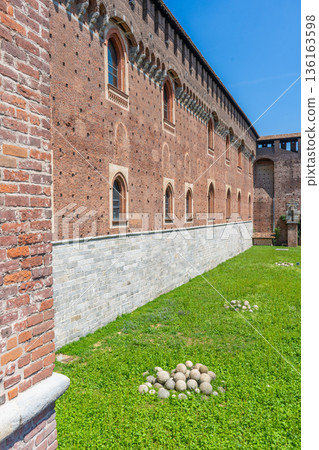 Cannonballs on the grass in Sforza ancient Italian architecture fort building. Old facade. Italy, Milan Cannonballs on the grass in Sforza ancient Italian architecture fort building. Old facade. Italy, Milan 136163598