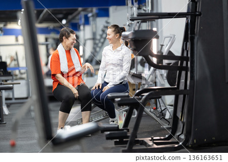Senior woman and coach discussing exercise in gym Senior woman and coach discussing exercise in gym 136163651