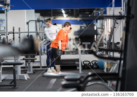Personal trainer guiding woman during strength training workout Personal trainer guiding woman during strength training workout 136163700
