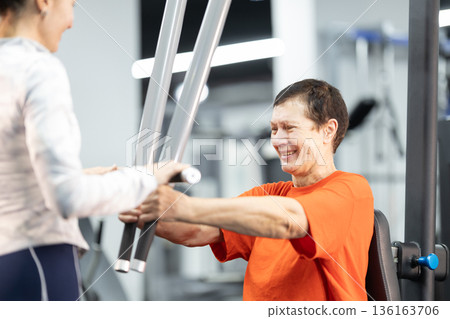 Senior woman smiling while exercising with personal trainer 136163706