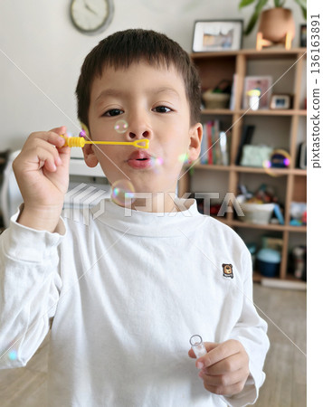 Boy Blowing Bubbles In Home Environment With Joyful Expression Boy Blowing Bubbles In Home Environment With Joyful Expression 136163891
