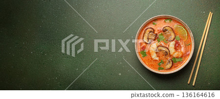 Tom yum soup with shrimp and mushrooms in bowl with chopsticks top view, traditional Thai soup Tom yum soup with shrimp and mushrooms in bowl with chopsticks top view, traditional Thai soup 136164616