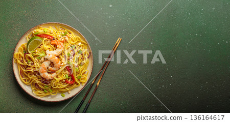 Pad thai noodles with shrimp, peanuts and lime on green background, dish of Thailand. Space for text 136164617