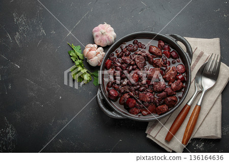Brazilian feijoada with black beans, sausage and meat in a pot, top view with space for text Brazilian feijoada with black beans, sausage and meat in a pot, top view with space for text 136164636