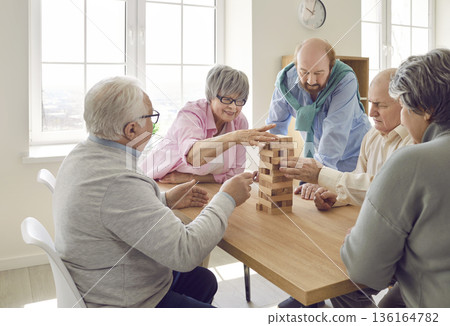 Group of senior men and women playing together with wooden building blocks for dementia therapy. Group of senior men and women playing together with wooden building blocks for dementia therapy. 136164782