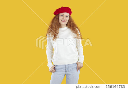 Portrait of happy smiling young woman in red beret, dressed in white sweater and light blue jeans. Portrait of happy smiling young woman in red beret, dressed in white sweater and light blue jeans. 136164783