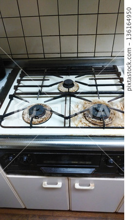 A three-burner household gas stove that has accumulated burnt food and oil stains over the years A three-burner household gas stove that has accumulated burnt food and oil stains over the years 136164950
