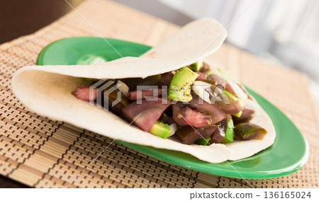 salad of black tomatoes, avocado and onions in Italian tortilla on green plate salad of black tomatoes, avocado and onions in Italian tortilla on green plate 136165024