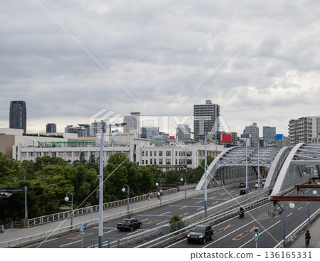 Under a cloudy sky, roads with cars and city buildings 136165331