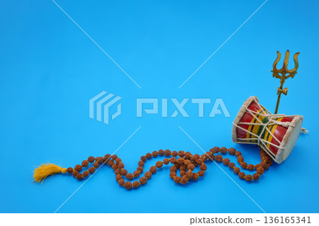 Maha Shivratri. Hindu damru, trishula, and rudraksha mala on blue background 136165341