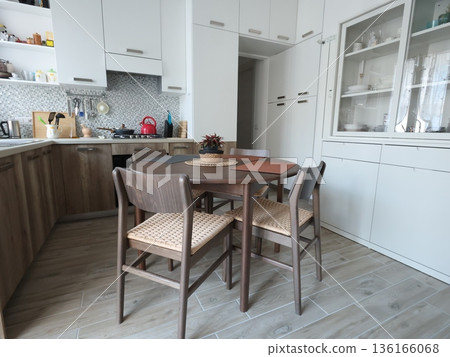 Living room design combined with kitchen, featuring white sideboard. Set of wooden furniture with beech veneer, table, and chairs. Scandinavian-style interior. Minimalism and modern renovation. Living room design combined with kitchen, featuring white sideboard. Set of wooden furniture with beech veneer, table, and chairs. Scandinavian-style interior. Minimalism and modern renovation. 136166068