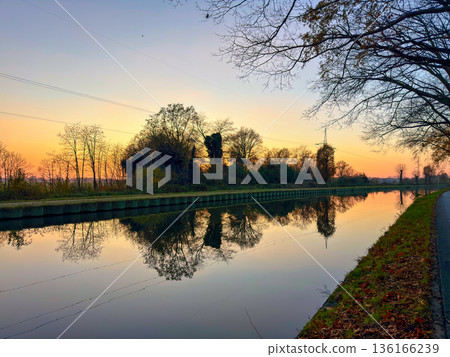 Rijkevorsel, Antwerpse Kempen, Belgium, Calm canal reflecting soft sunset colors and silhouetted Rijkevorsel, Antwerpse Kempen, Belgium, Calm canal reflecting soft sunset colors and silhouetted 136166239