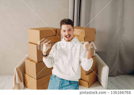 Happy young man portrait moving with cardboard boxes to new estate home apartment. Happy young man portrait moving with cardboard boxes to new estate home apartment. 136166768