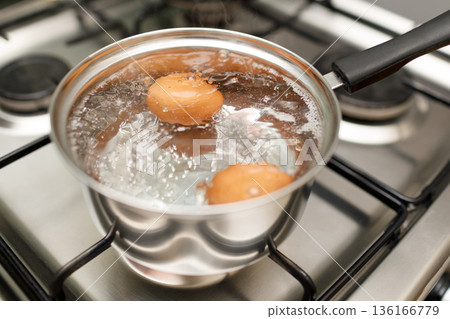 Saucepan stainless steel with boiling eggs breakfast in water on gas stove. 136166779