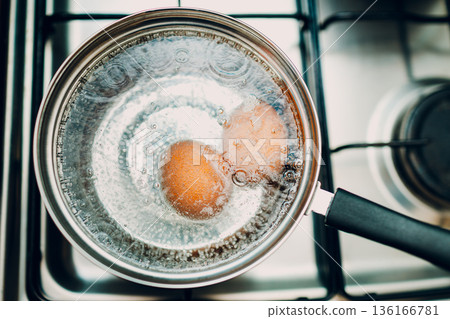Saucepan stainless steel with boiling eggs breakfast in water on gas stove. 136166781