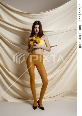 young slender brunette posing full-length in studio against fabric background. 136167682