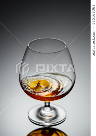 Drop of brandy fall into a glass. Drop of brandy fall into a glass. 136168362