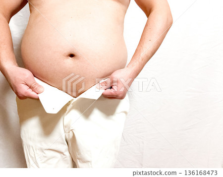 Obese middle-aged man putting on pants 136168473