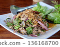 Appetizing platter of spicy Thai Larb Moo minced pork salad with fresh herbs red onions chilies and crispy fried shallots served with refreshing green vegetables. 136168700