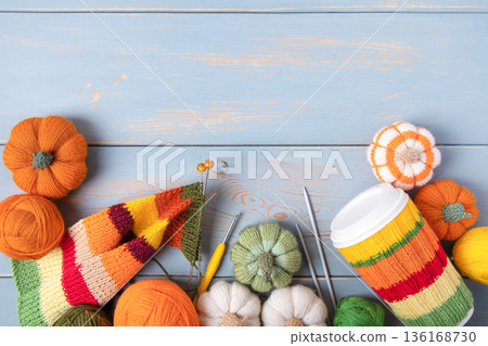 Blue wooden work desk with knitting and needlework tools. Knitting toys, warm clothes, and coffee cup covers. A hobby for winter and autumn 136168730