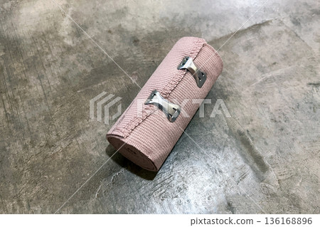 single rolled elastic medical compression bandage with clips on grey concrete floor single rolled elastic medical compression bandage with clips on grey concrete floor 136168896