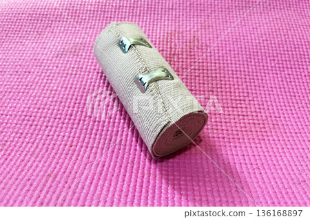 rolled elastic medical compression bandage on bright pink textured mat 136168897