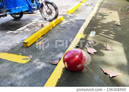 motorcycle helmet on concrete ground next to yellow parking barrier and vehicle wheel in bright sunlight motorcycle helmet on concrete ground next to yellow parking barrier and vehicle wheel in bright sunlight 136168900
