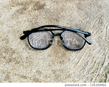 black plastic frame eyeglasses laying on rough gray concrete floor black plastic frame eyeglasses laying on rough gray concrete floor 136168902
