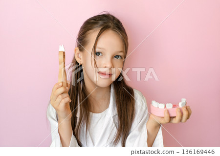 Child with dental tool and jaw model symbolizing first milk tooth loss, pediatric dentistry care, oral health prevention, and professional dental clinic services for World Oral Health Day. Child with dental tool and jaw model symbolizing first milk tooth loss, pediatric dentistry care, oral health prevention, and professional dental clinic services for World Oral Health Day. 136169446